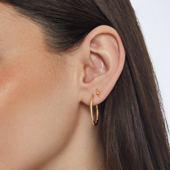 Gold Mini Metal Lightning Stud Earrings and Gold Medium Hoop Earrings on model