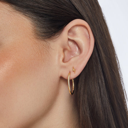 Gold Mini Metal Lightning Stud Earrings and Gold Medium Hoop Earrings on model
